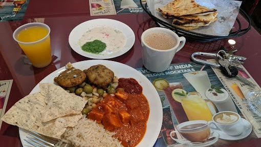 Indian food spread on a table: curry, rice, bread, drinks, plus keys and a napkin.