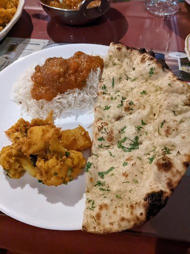 Plate of Indian food: rice, curry, cauliflower dish, and naan bread.