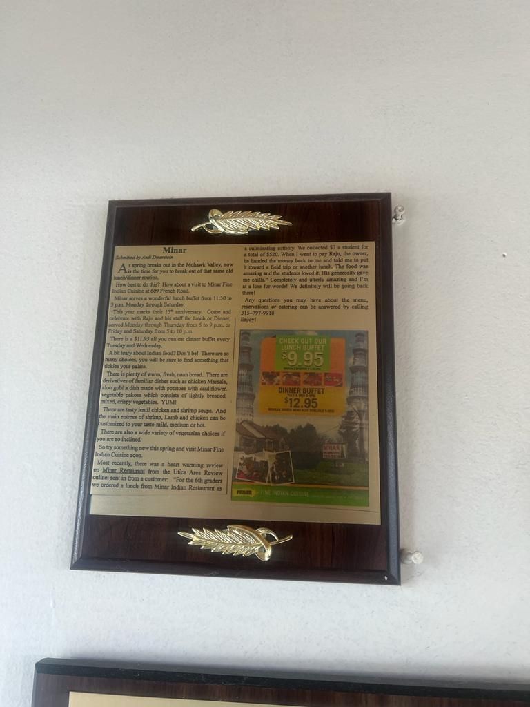 Wooden framed plaque with printed text and a colorful image, mounted on a white wall.