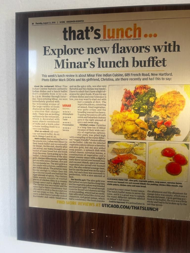 Framed newspaper article about Minar's lunch buffet, featuring food photos.
