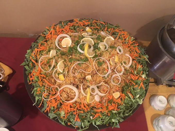 Large platter of food: rice, vegetables, lemon slices, onion rings.