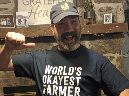 a man wearing a t-shirt that says world 's okayest farmer | Local beef for sale near me