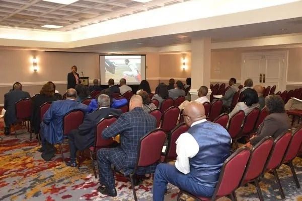 Conference audience seated in a hotel meeting room watching a presentation on a screen