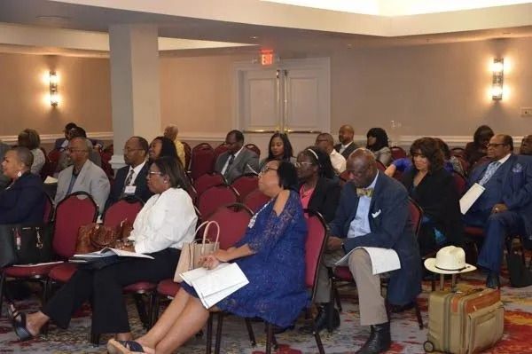 Audience seated in a conference room, listening attentively during a meeting.