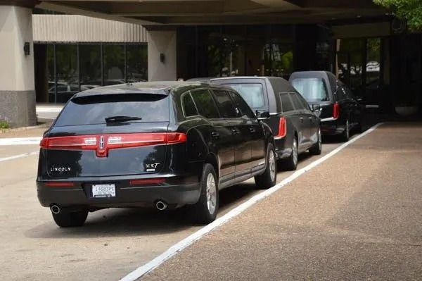 Black SUV parked in a covered parking area, with two more vehicles lined up behind it.