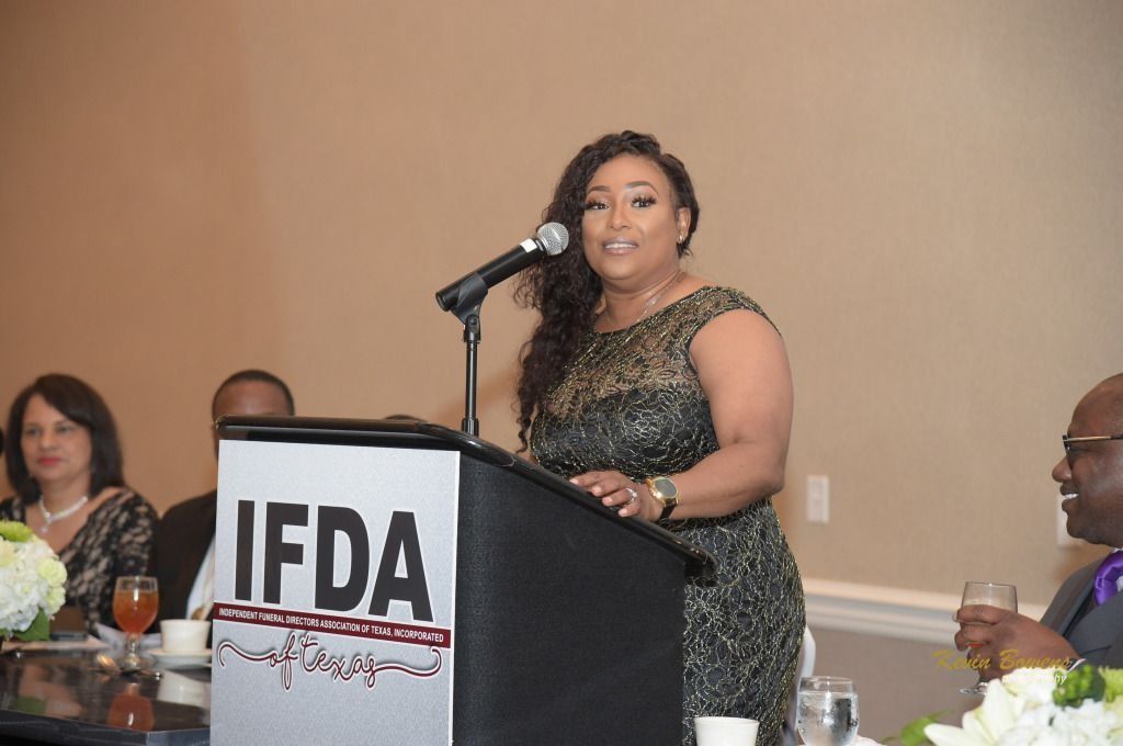 Woman speaking at a podium with an IFDA sign at a formal banquet event