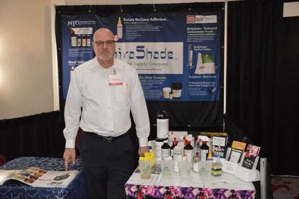 Man standing at a trade show booth with product display and banners behind him