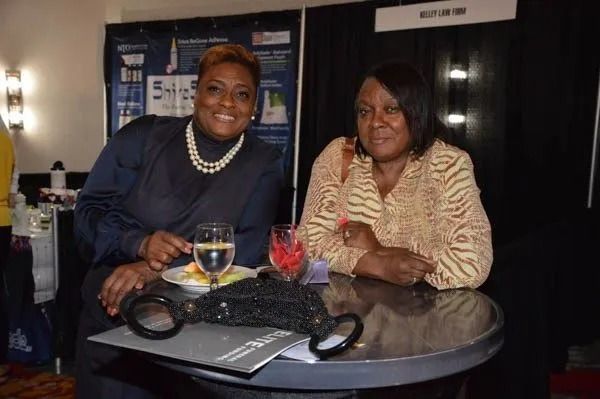 Two people seated at a round table with drinks, smiling in a dim indoor lounge