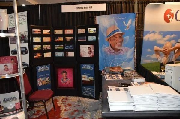 Trade show booth with brochures, product display panels, and a large blue promotional poster.