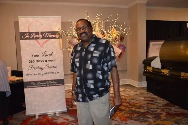 Man standing beside a birthday banner in a decorated banquet hall