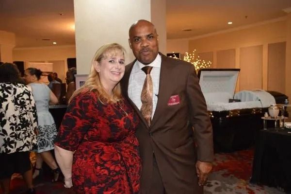 Two people posing at an indoor event, with a buffet table in the background