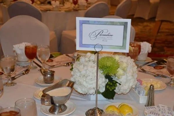 Elegant banquet table with white floral centerpiece, place settings, and a table card at a formal event