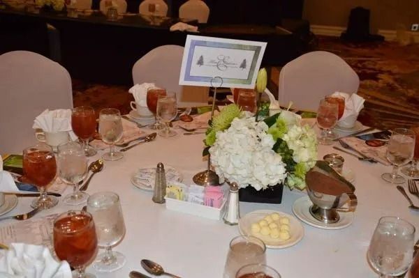 Elegant banquet table set with floral centerpiece, framed table card, tea, and glassware at a formal event