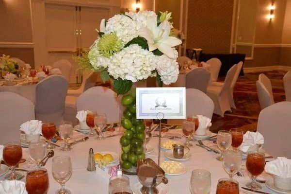 Banquet table centerpiece with white flowers, green grapes, and place settings at a reception venue