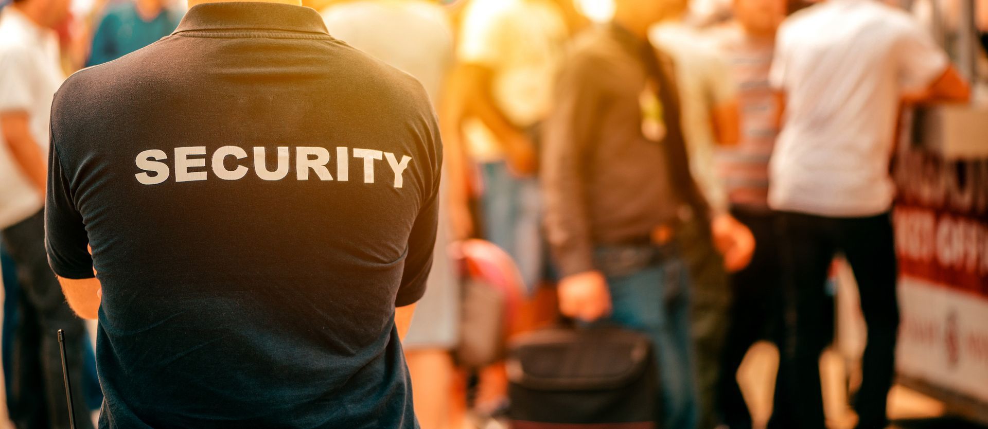 A security guard is standing in front of a crowd of people.