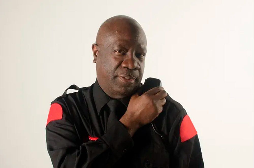 A man in a black and red uniform is talking on a walkie talkie.