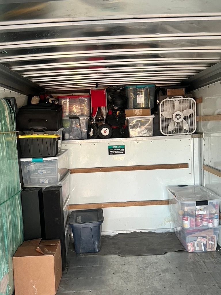 The inside of a moving truck filled with boxes and a fan.