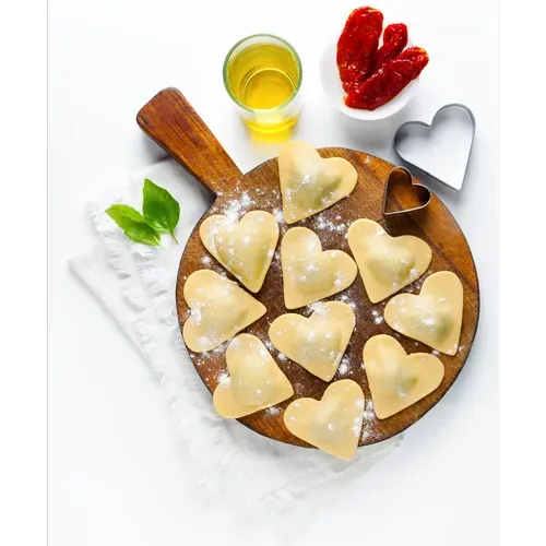 Heart-shaped pastry cookies on a wooden board with honey, strawberries, and mint on a white background