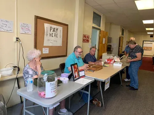 Volunteers at a pay table in a hallway, with a sign reading “PAY HERE.”