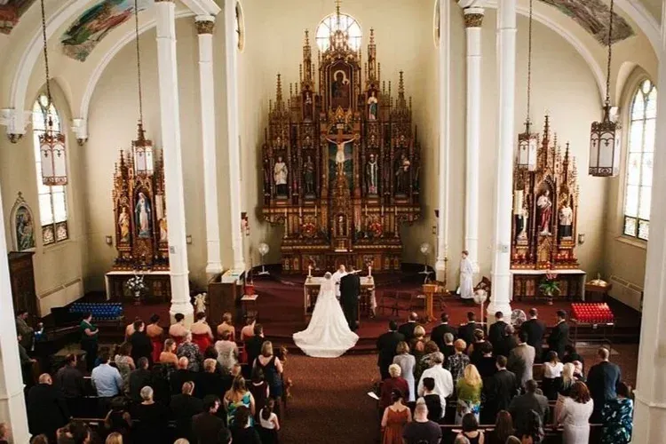Wedding ceremony in a church, with bride and groom at the altar before a large congregation.