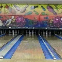 Bowling alley lanes with colorful overhead mural and pins set at the far end