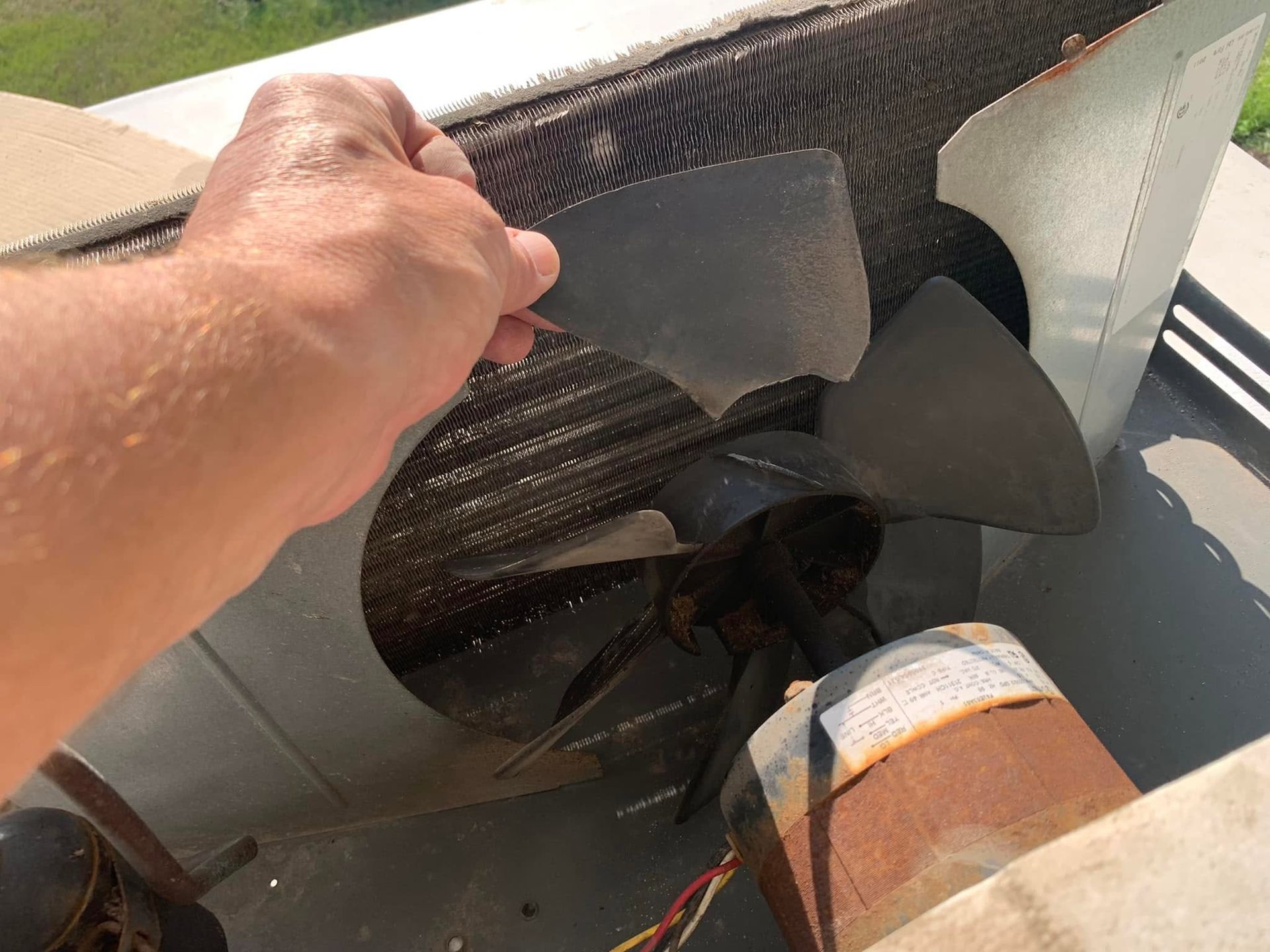 Hand holding a boat propeller on a motor, showing the black propeller and metal housing.