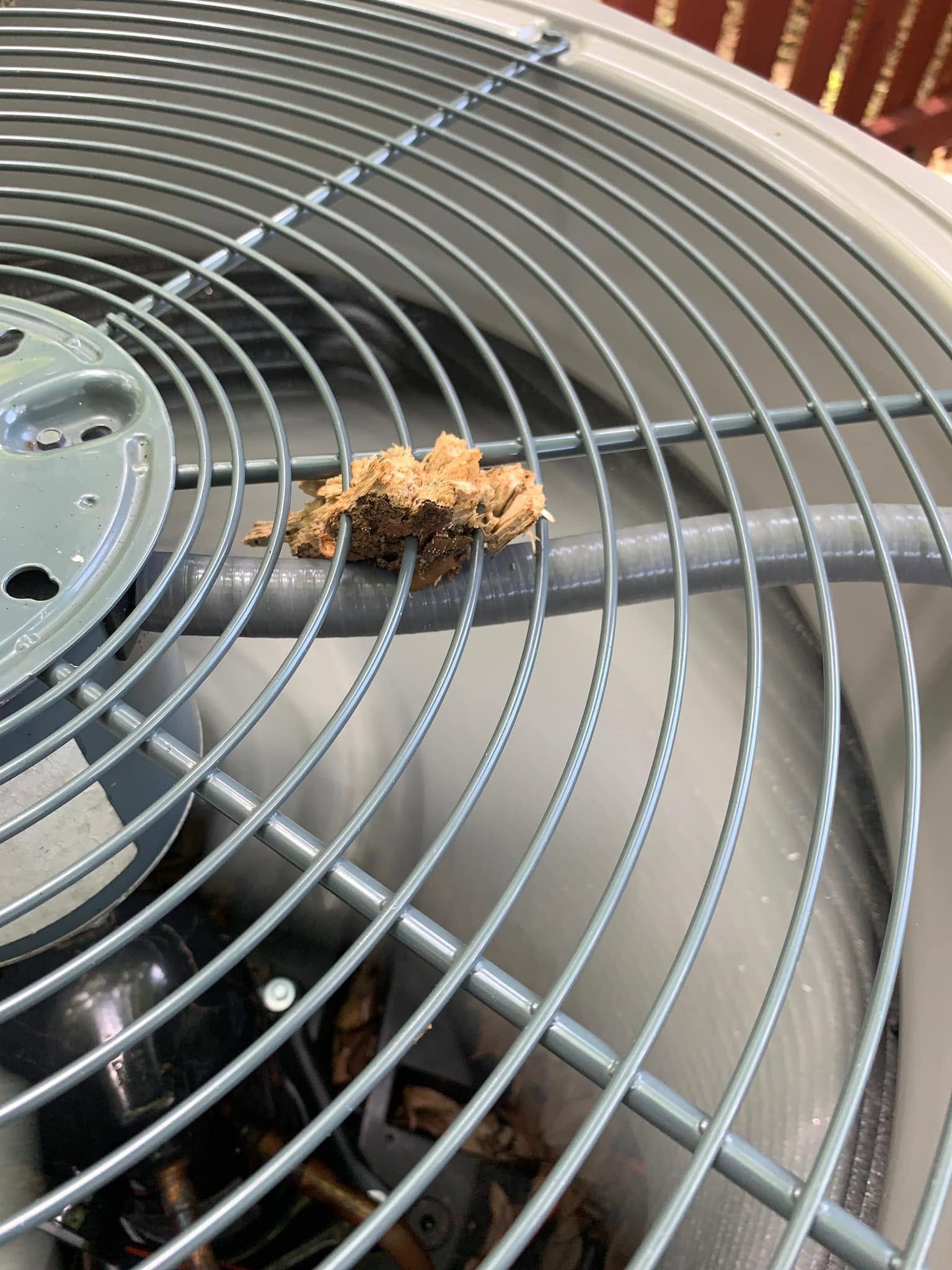 Dust buildup on a metal fan grille over a gray fan blade.