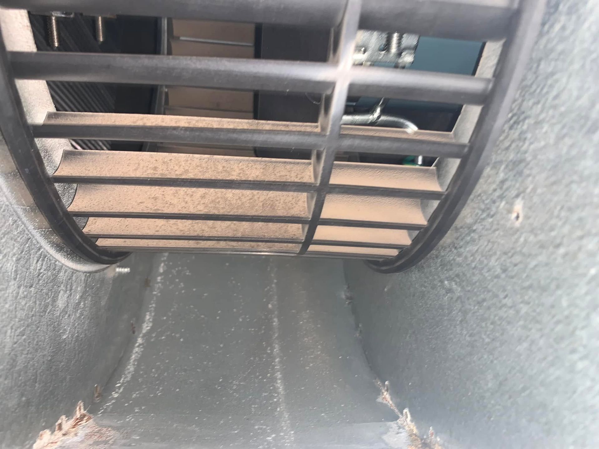 Close-up of a vent grille over a beige interior surface with gray textured walls.