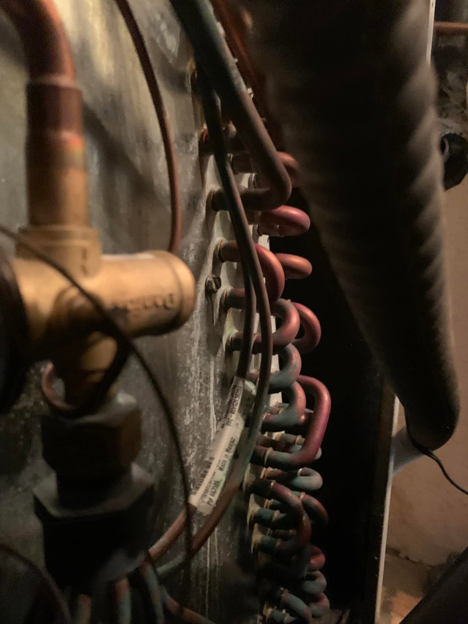 Close-up of coiled pink tubing and dark metal pipes in an industrial setting