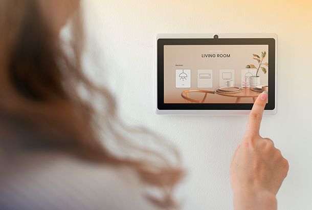 A person touches a wall-mounted smart home control panel displaying living room settings.