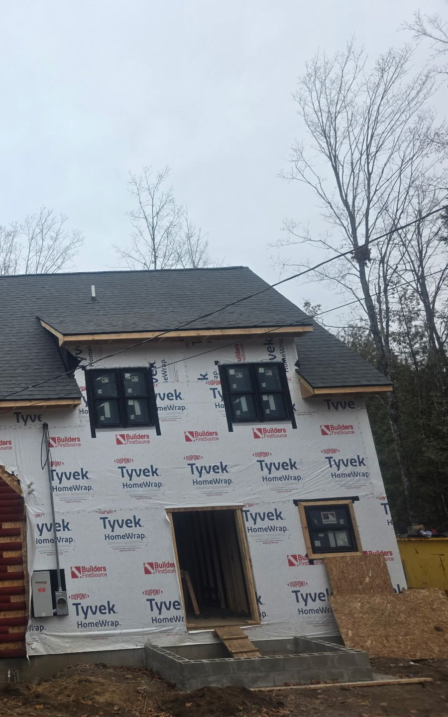 Progress photo of a two-story house with siding and window installation.
