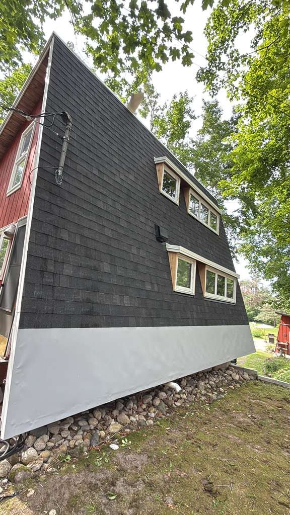 A red house with an A-line roof featuring an asphalt shingle installation