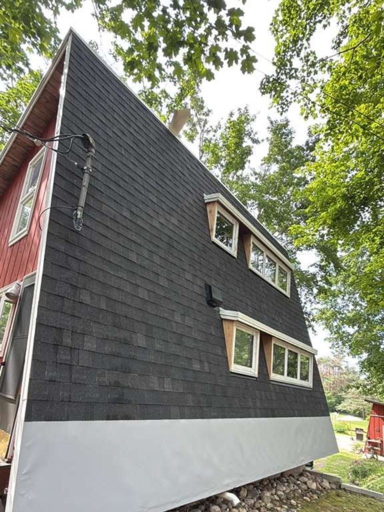 A red house with an A-line roof featuring an asphalt shingle installation
