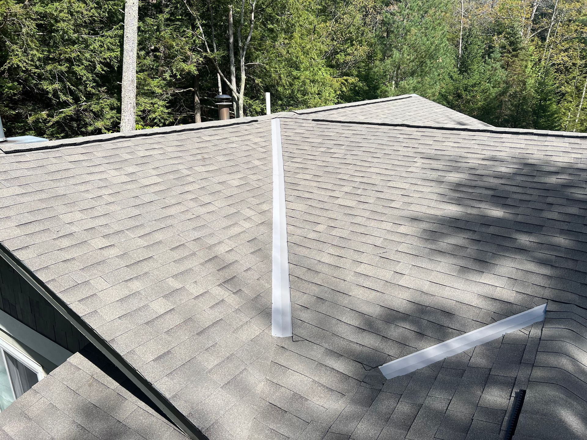 Aerial view of a light grey asphalt shingle roof installation.