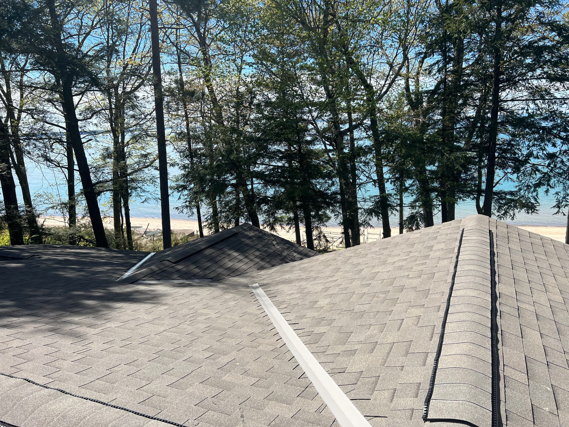 Aerial view of a grey asphalt shingle roof installation by Alpine Brothers Construction