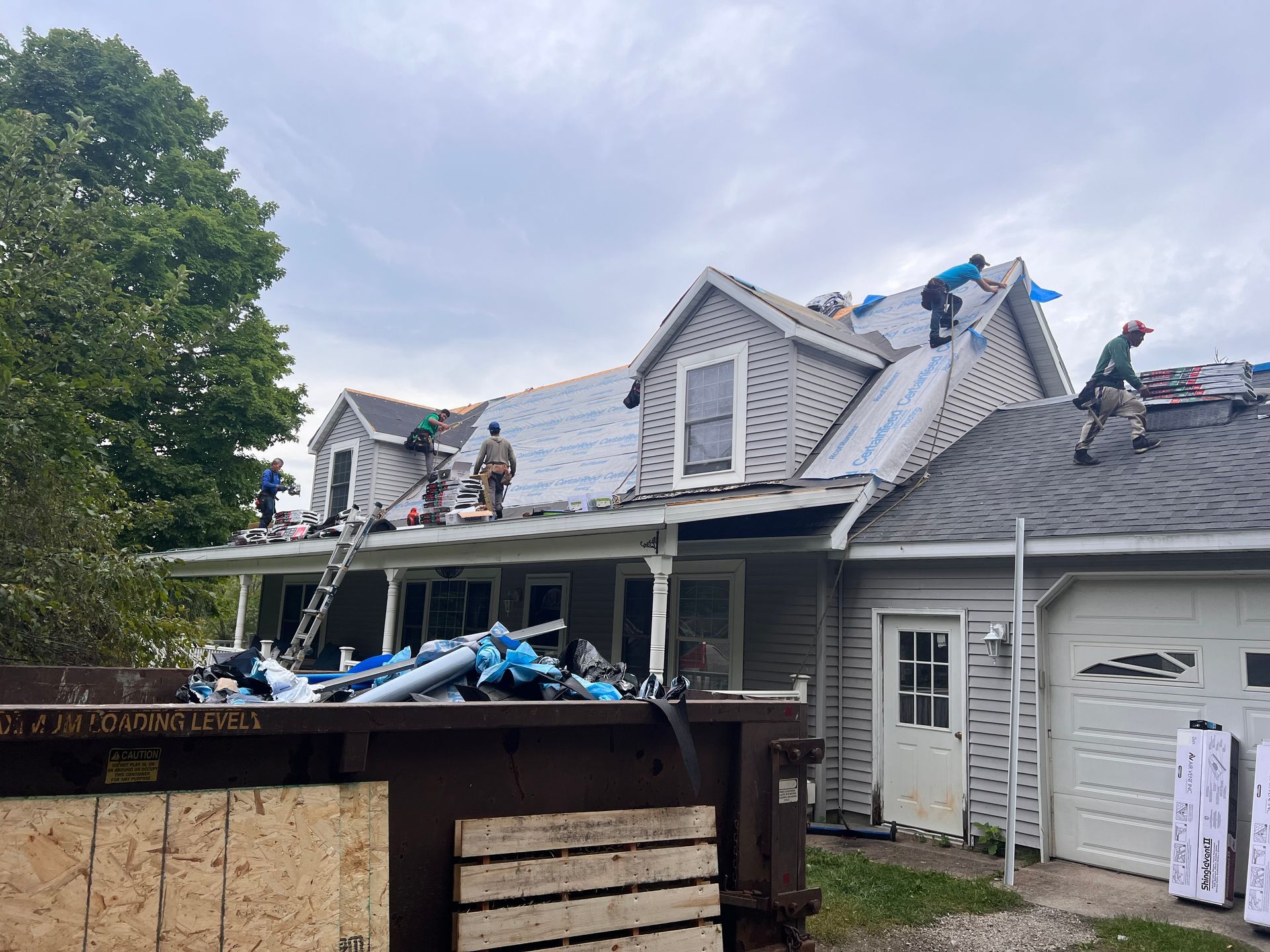 Alpine Brothers Construction team working on a two-story home's asphalt shingle roof replacement.