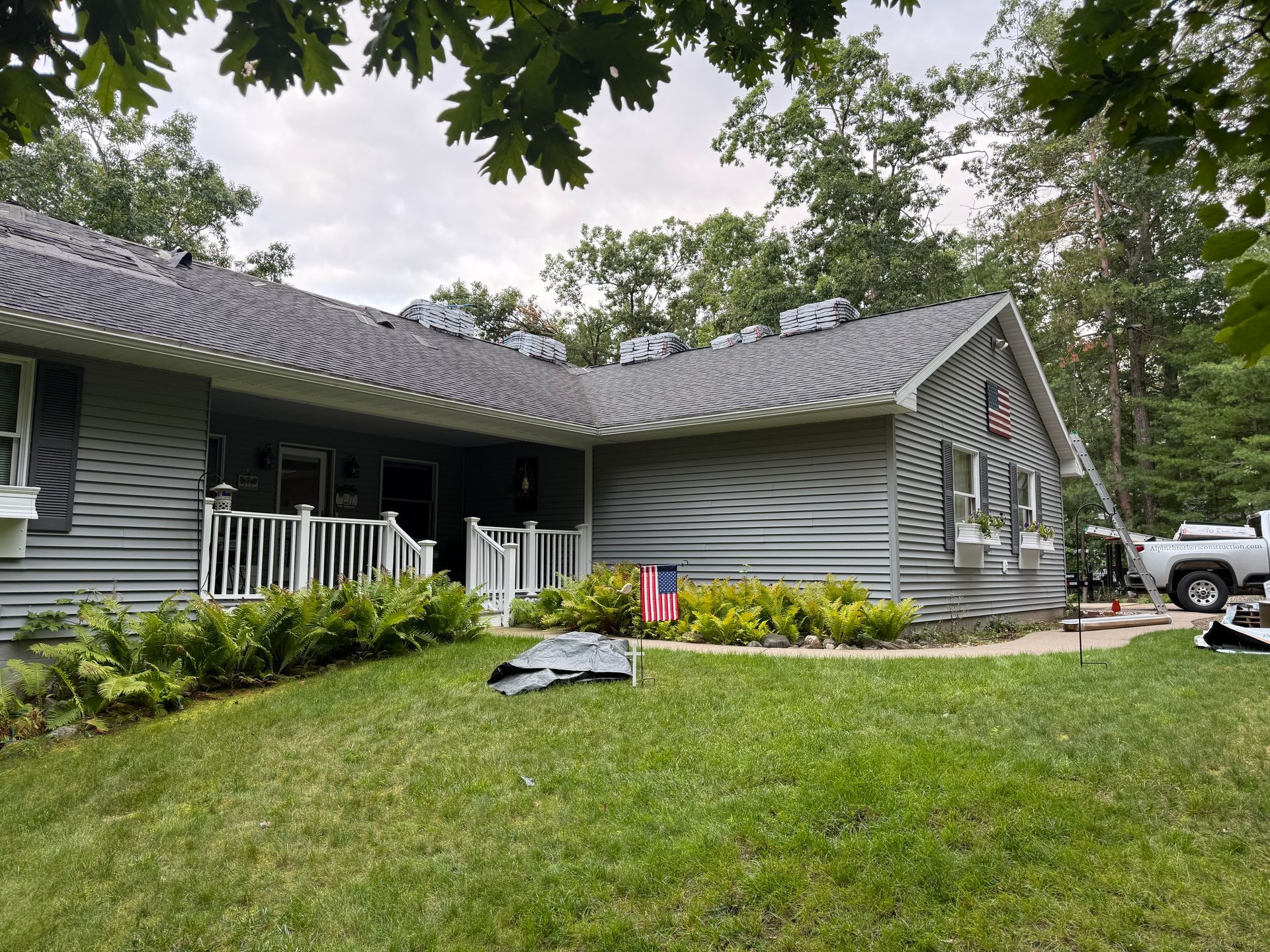 House with light grey vinyl siding and a nearly finished asphalt roof replacement.