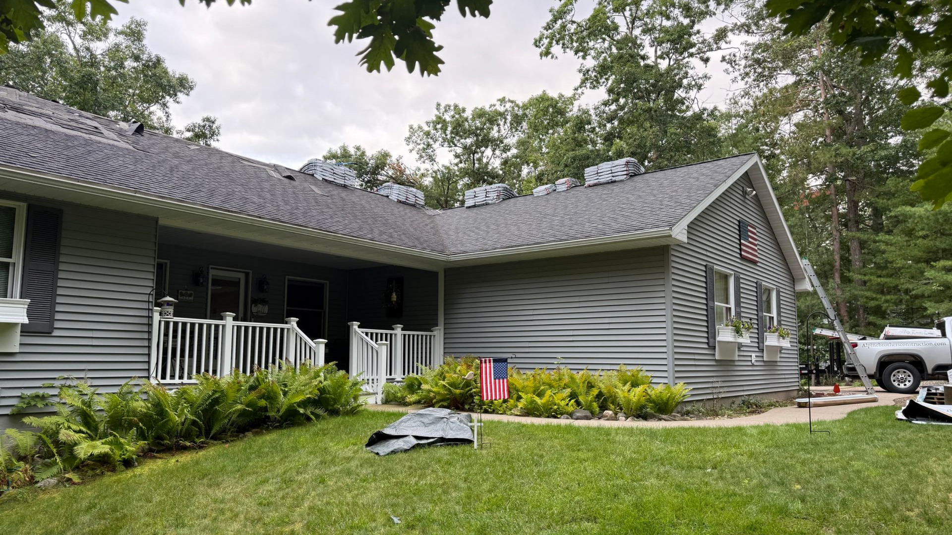 A grey, one-story house with a newly shingled roof by Alpine Brothers Construction