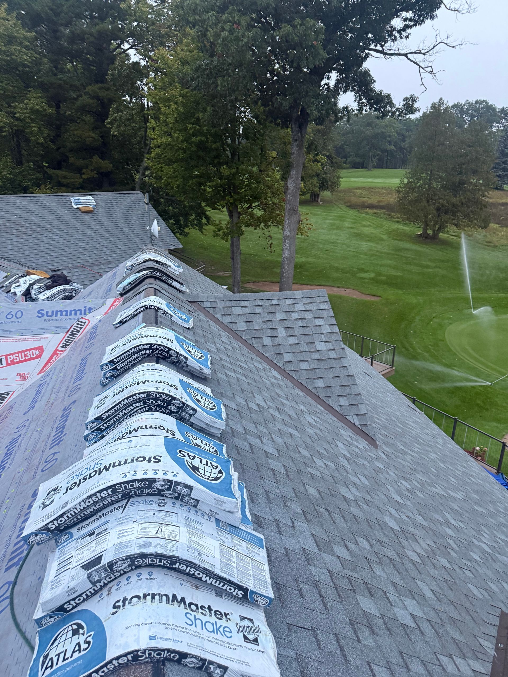 A roof in Gaylord, MI with theCom first courses of architectural asphalt shingles, with shingle bundles ready on the ridge.