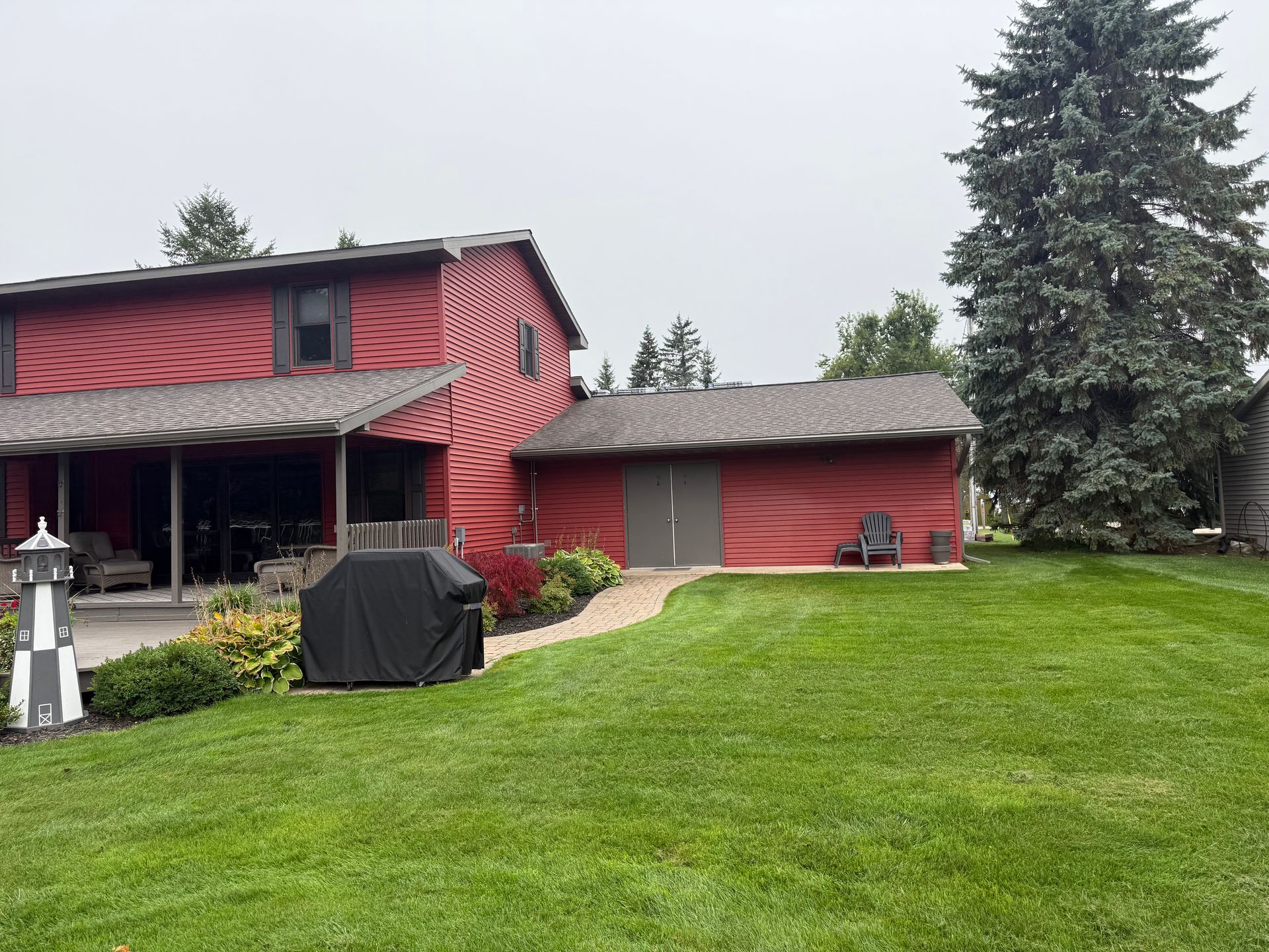 House with red siding and a new asphalt roof installation in Gaylord, GI