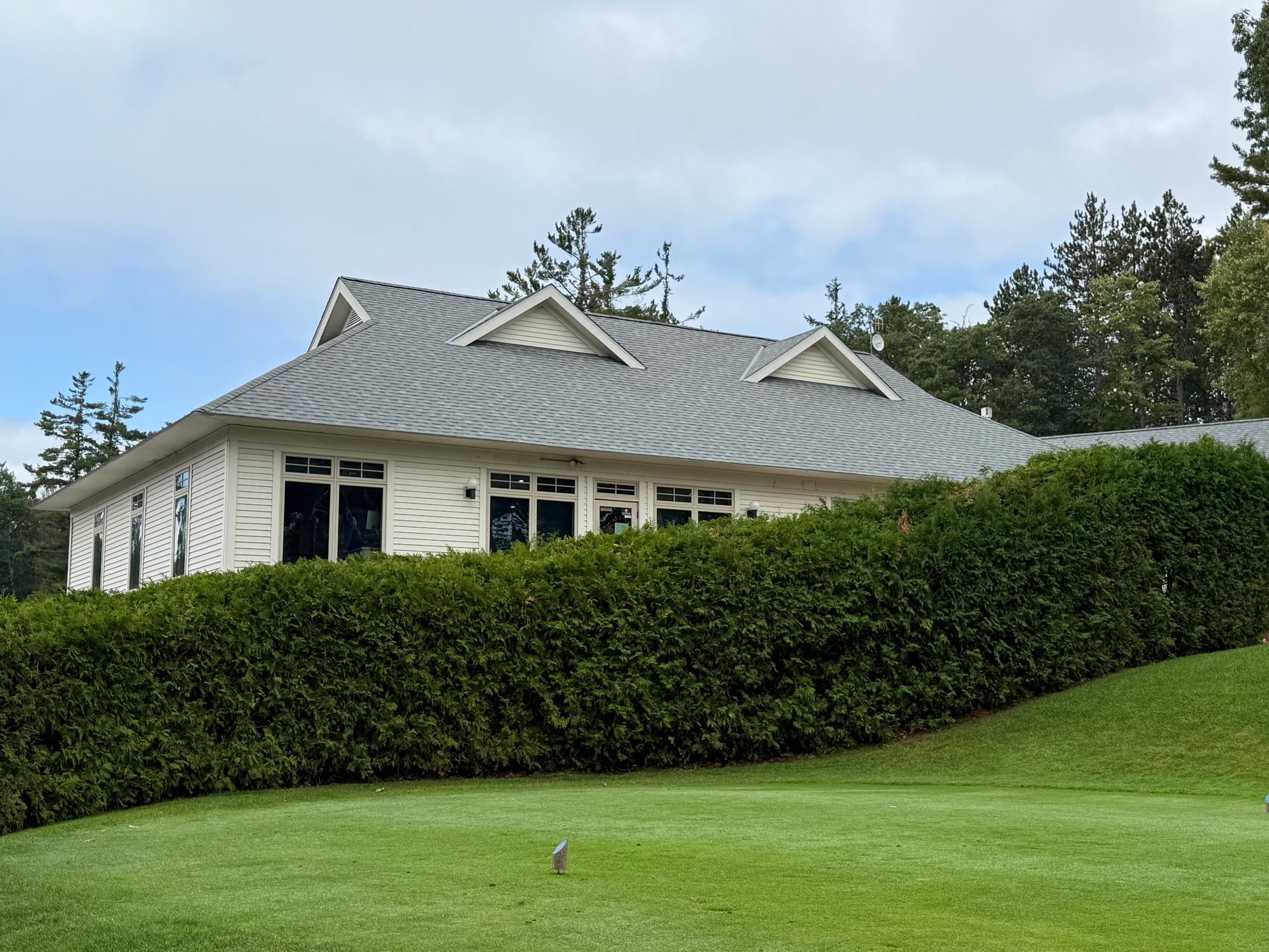 Commercial single story building with white siding and light grey shingle installation by Alpine Brothers Construction