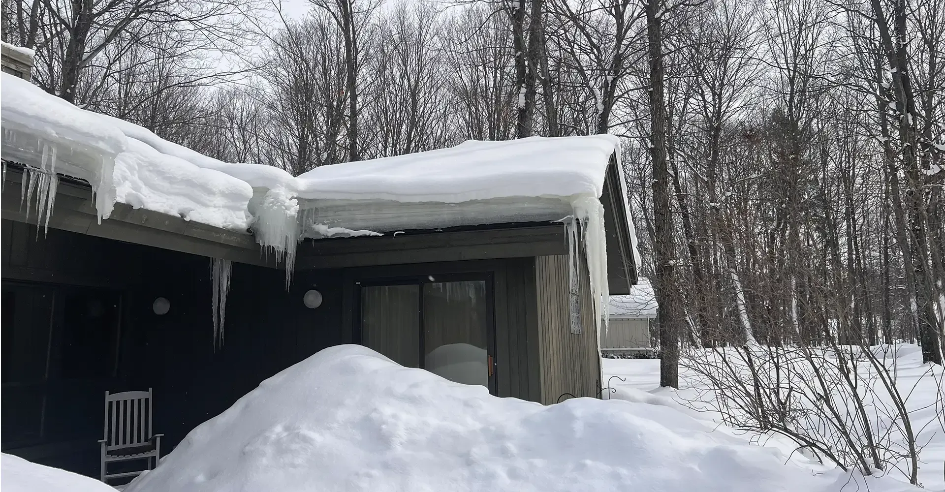 Dark house with thick ice dams on the roof in Gaylord, MI