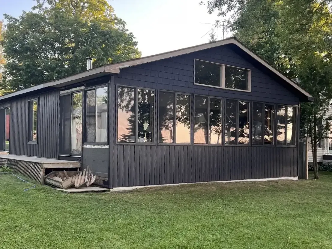 Single-story home with dark siding and new window installation by Alpine Brothers Construction.