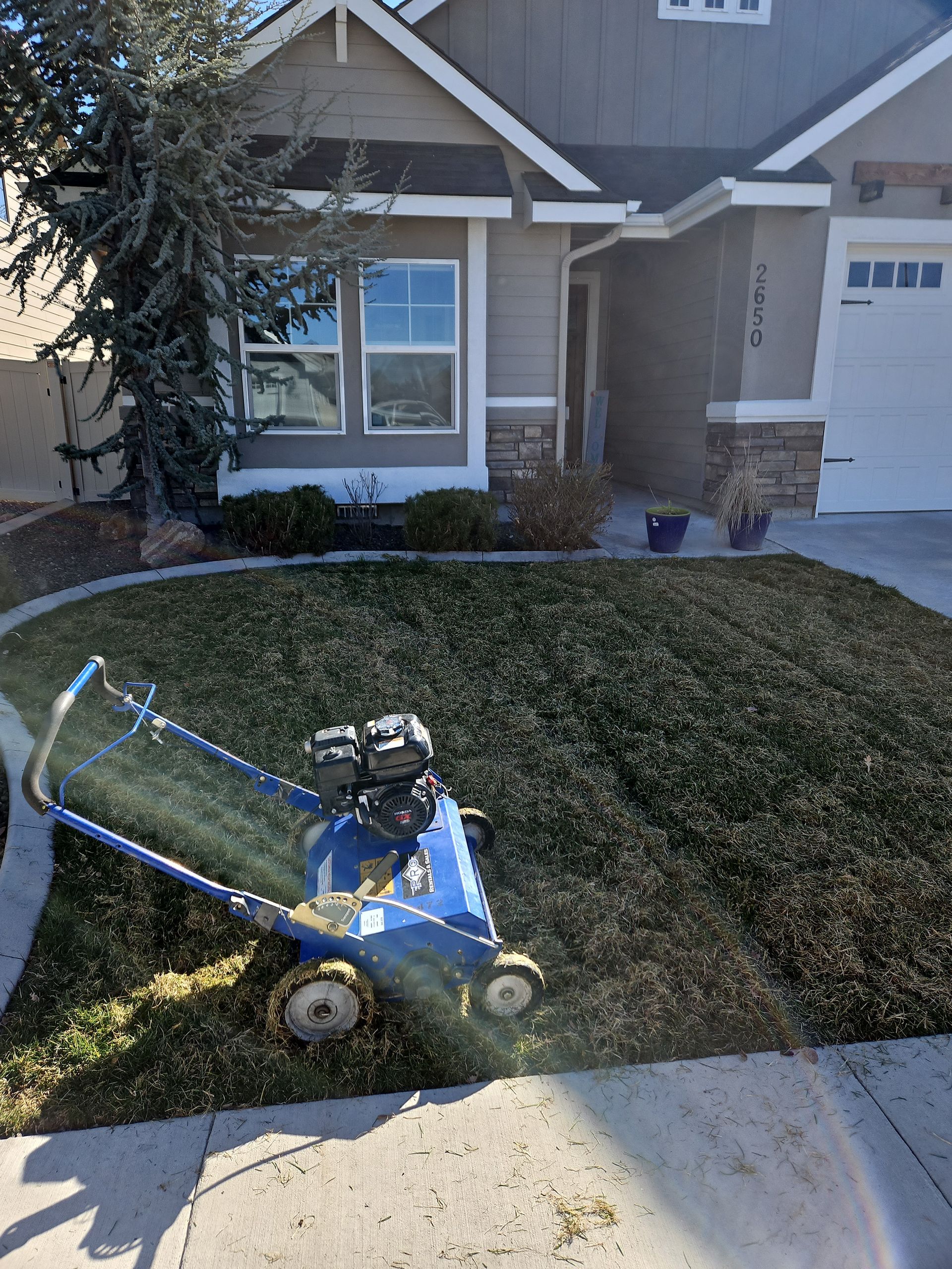 Aerating machine on a lawn in front of a house, sunny day.