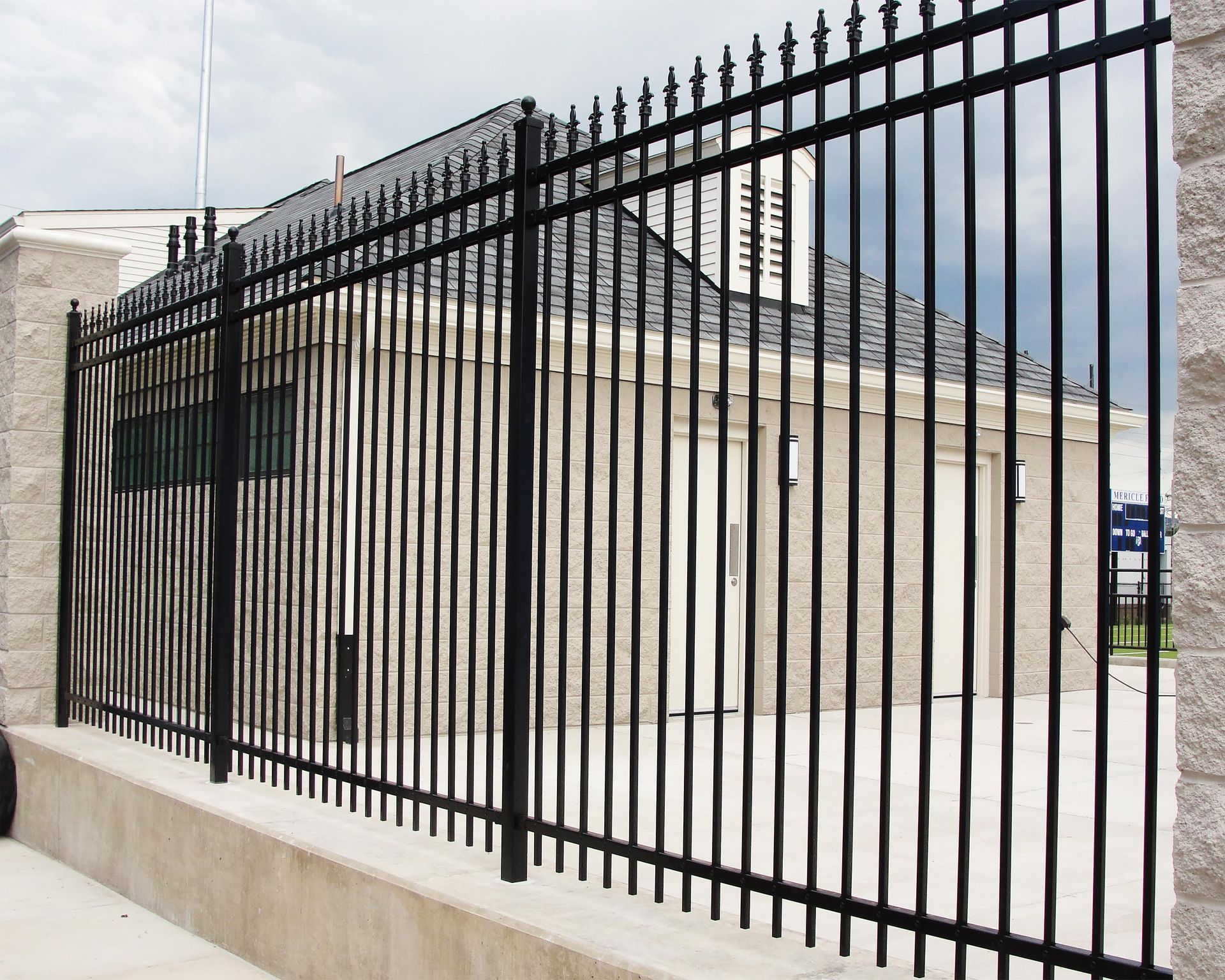 A close up of a wrought iron fence with trees in the background.