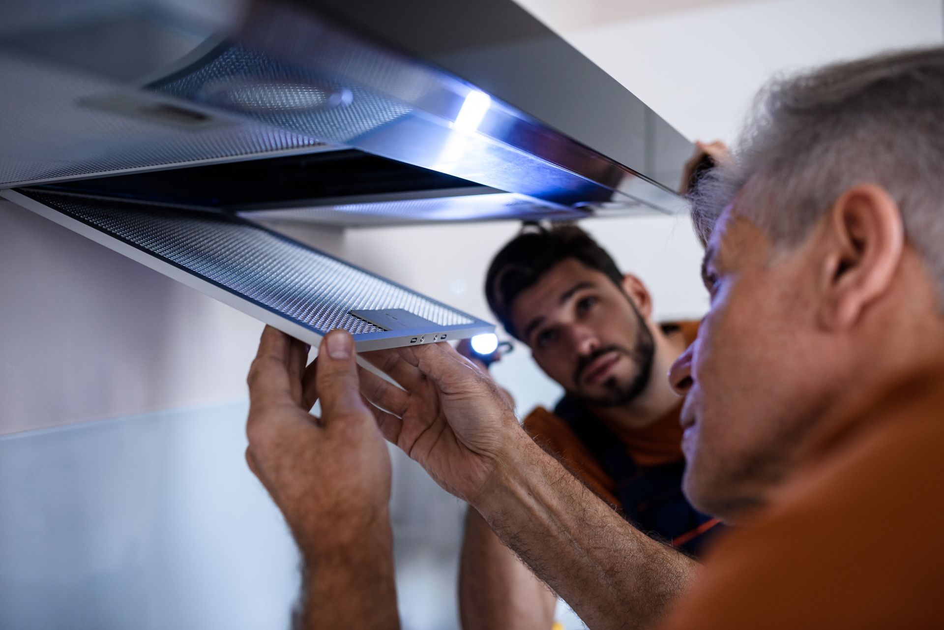 Two workers in uniform looking up at a kitchen extractor to access cleaning. Two workers in uniform looking up at a kitchen extractor to access cleaning.