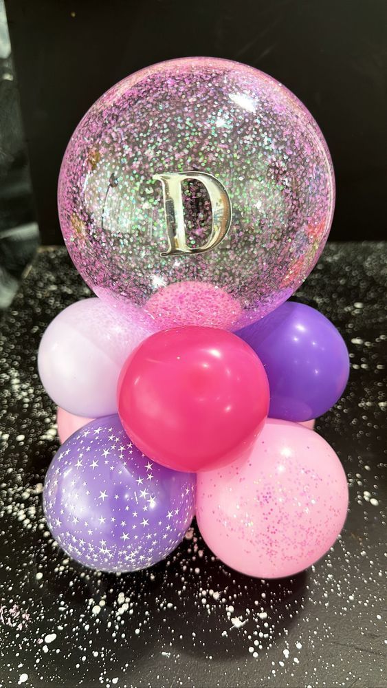 Pink and purple balloon centerpiece with glitter and a letter 