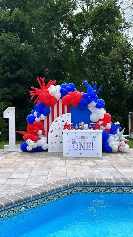 Patriotic first birthday setup with balloons by a pool. 