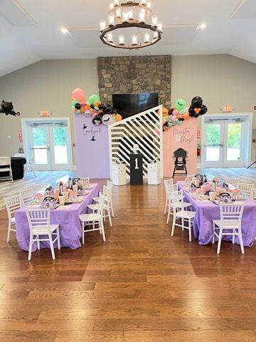Party room decorated with tables, balloons, and a backdrop for a first birthday.