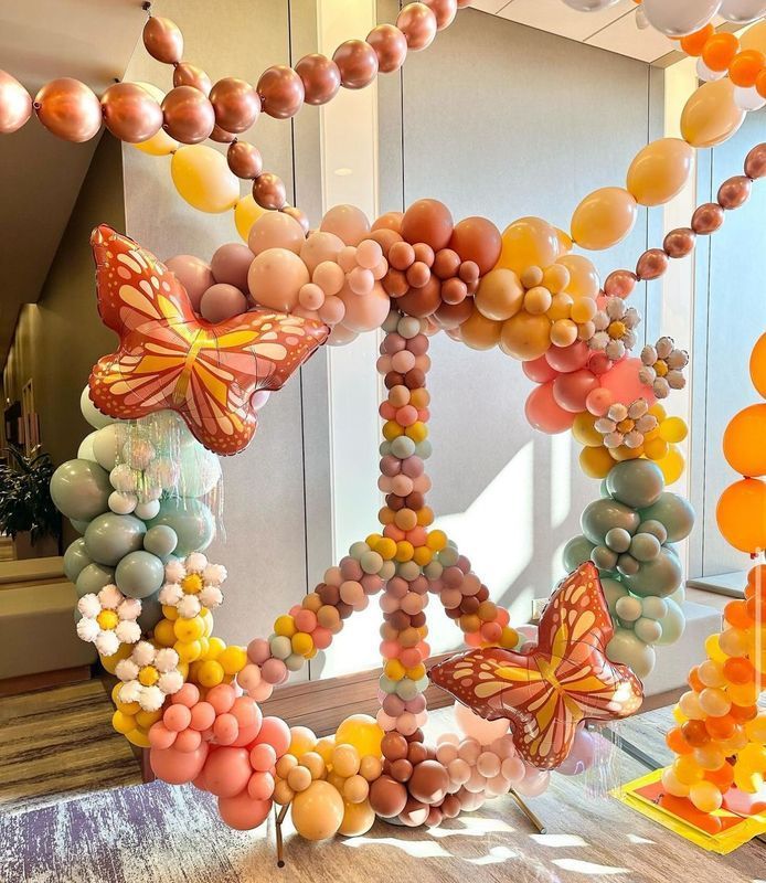 Peace sign balloon sculpture with butterflies, in shades of pastel colors.